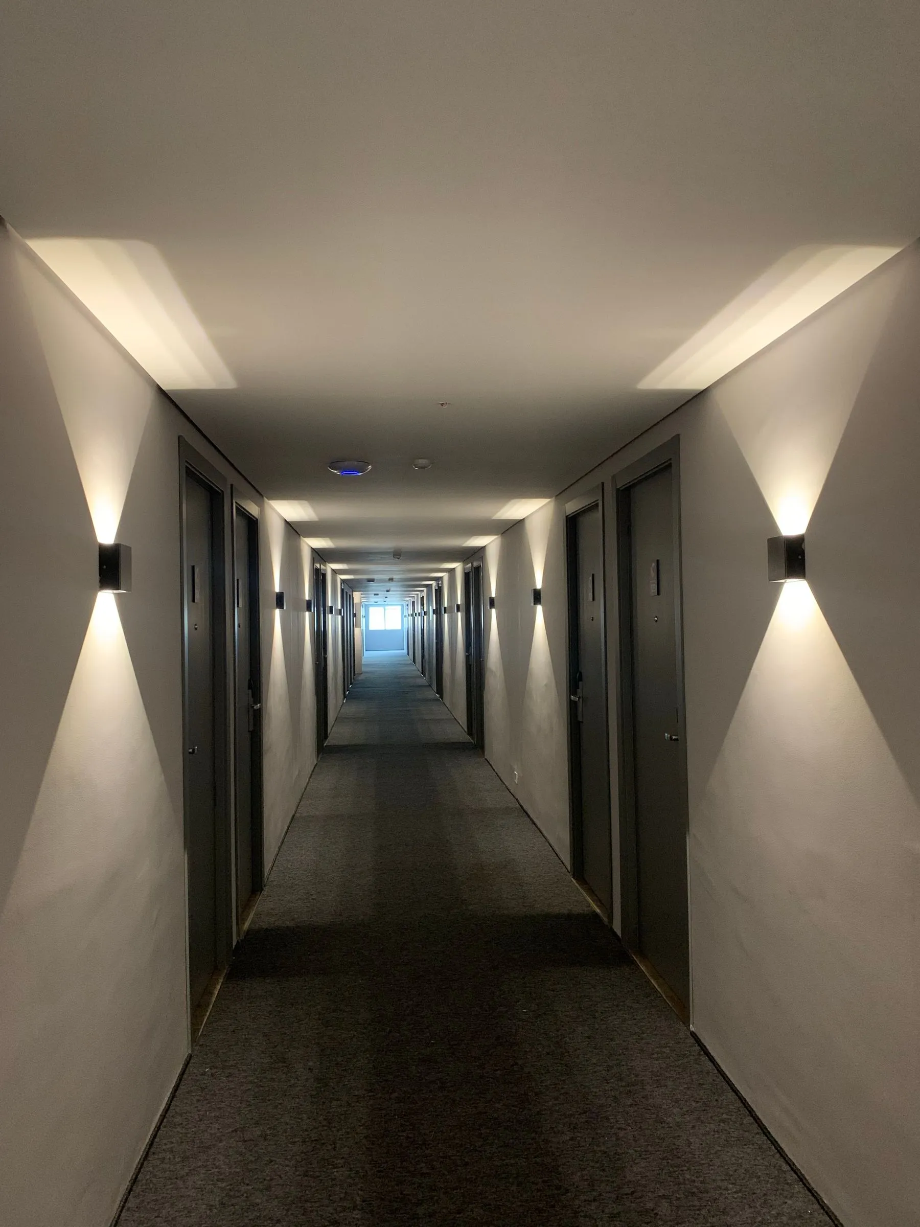 A grand-hotel corridor lit by warm sconces